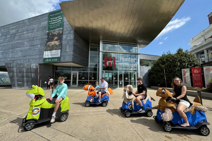 a group of people sitting on a motorcycle in front of a building