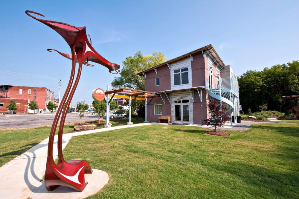 Modern sculpture and brick building with blue stairs in a grassy area.