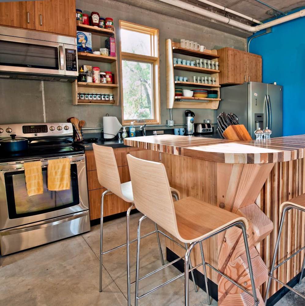 Modern kitchen with wooden island, stainless appliances, and blue accent wall.